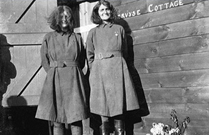Two women outside a wooden building