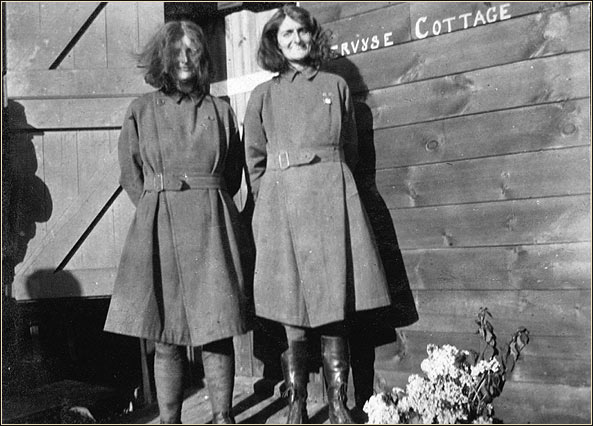 Two women outside a wooden building