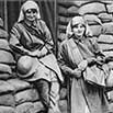 Two women beside wall of sandbags