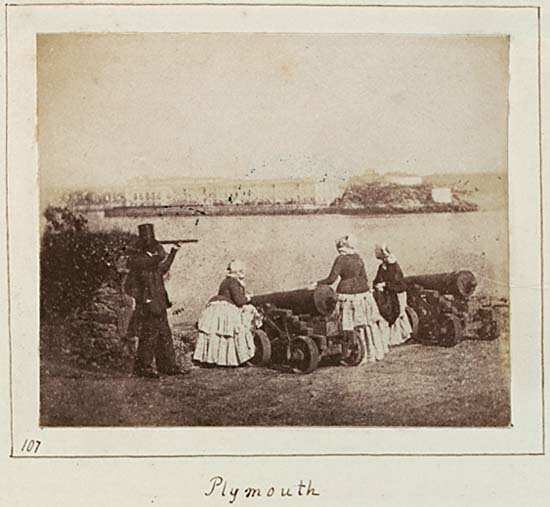 Three women and one man beside cannons looking out to sea at Plymouth.