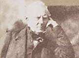 Hugh Lyon Playfair, leaning against an early photographer's posing chair with his elbow on a head rest.