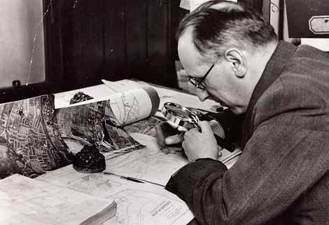 Photo of man looking at map through magnifying glass