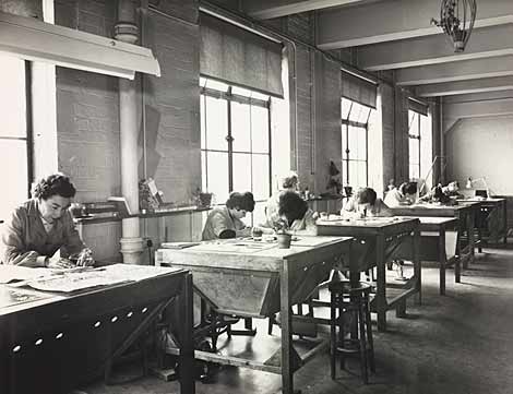 Photo of women seated at work tables looking down