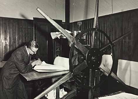 Photo of man working at a copperplate printing press