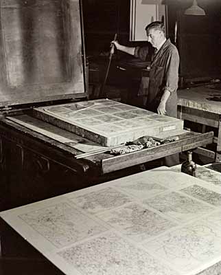 Photo of man standing at lithographic stone with map sheet on it