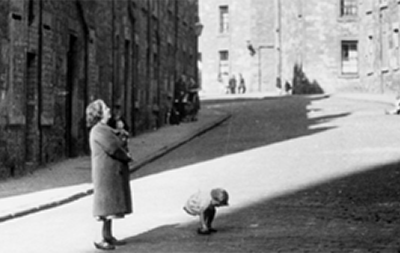 Film still of woman and children in street