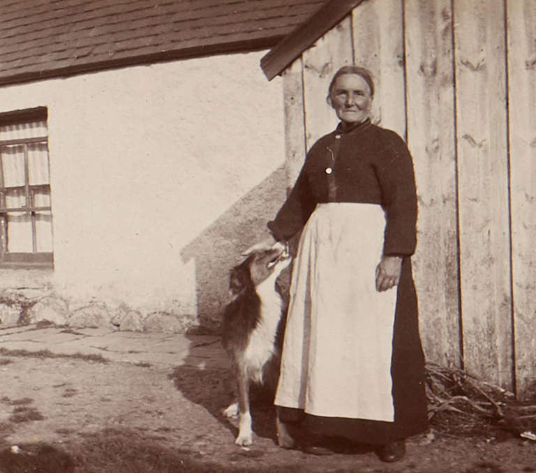 Photograph of woman standing in front of barn with dog