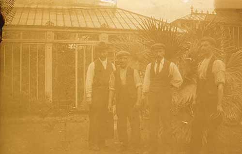 Photo of 4 men standing outside a large greenhouse